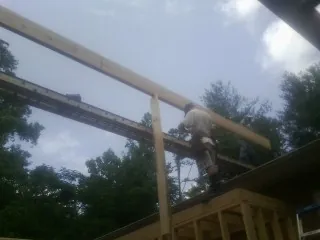 Carpenter setting a ridge beam over a new addition frame — Ice Dam Removal by Roofing Brothers in Benedict