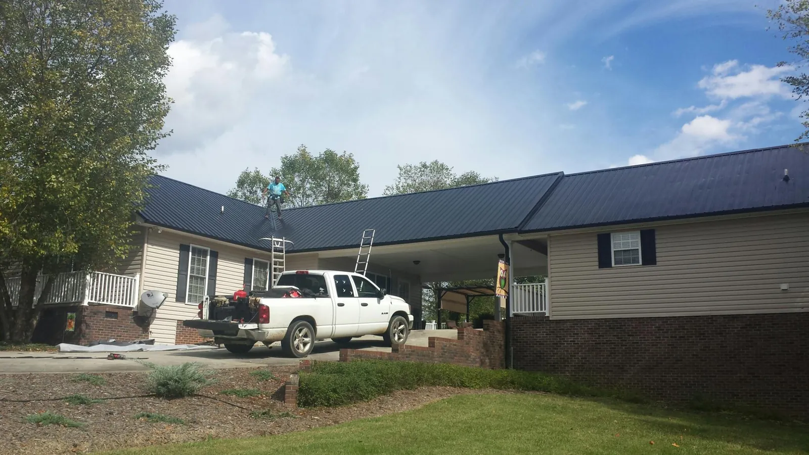 Black metal roof over a home and attached breezeway with ladders set in Benedict