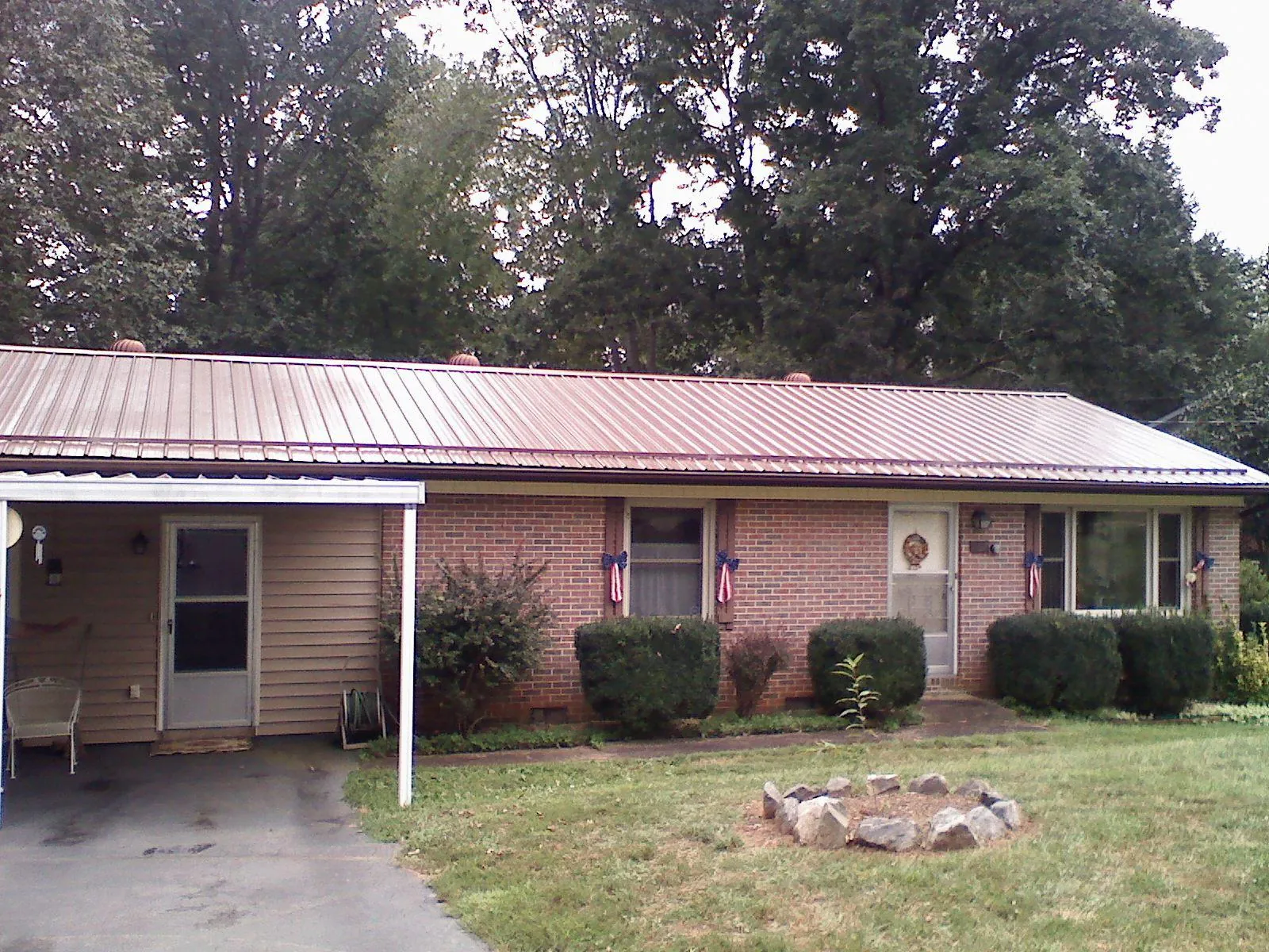 Bronze metal roof and carport on a brick ranch home — Roof Repair work by our crew in Benedict
